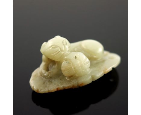 A Chinese pale jade netsuke, in the form of a recumbent cat with an insect, mottled brown inclusions, 4cm wide