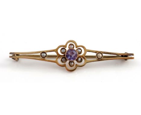 An Edwardian 9ct gold, amethyst and split pearl brooch, the central facet cut stone within a six petal open frame of half pea