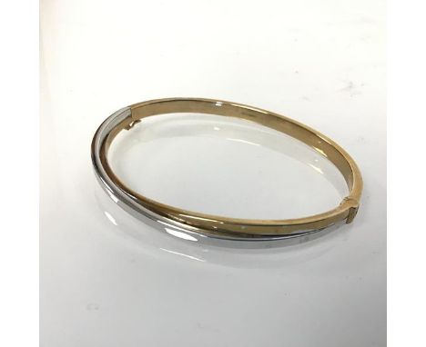 A 9ct yellow and white gold crossover stiff hollow hinged bangle (d.6.7cm x 5.5cm)
