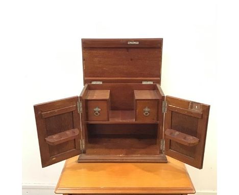 An Edwardian mahogany smoker's cabinet, the hinged top and front doors enclosing a pipe rack and pair of drawers for tobacco 