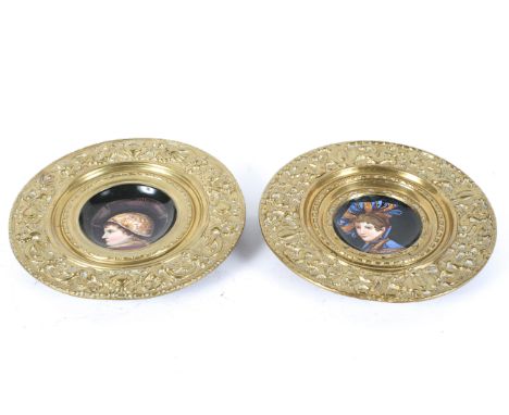 A pair of Continental brass chargers, with a central porcelain plaque painted with a portrait inside and embossed brass borde