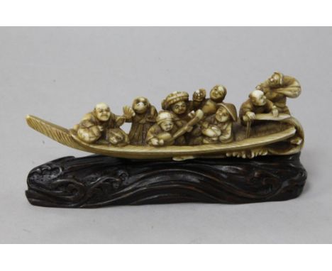 A Japanese ivory okimono of figures enjoying festivities on a boat, Meiji period, playing music and wearing costume and masks