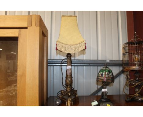 A brass columned table lamp raised on paw feet with shade 