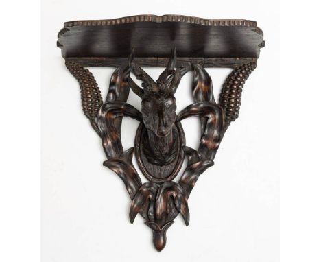 A late 19th/early 20th century Black forest carved wood wall bracket: the shaped open shelf on a carved maize support with re