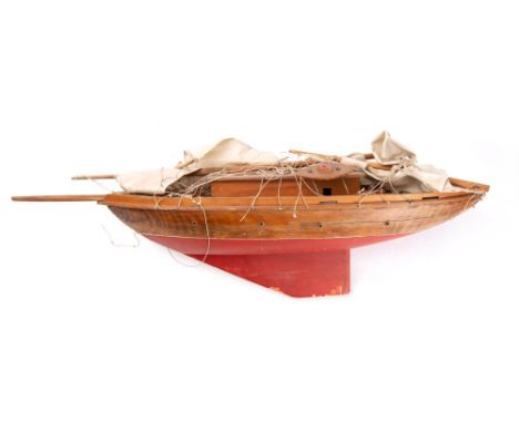 A 20th century model pond yacht: the simulated planked deck with cabin and fixtures and fittings over a pine hull painted red
