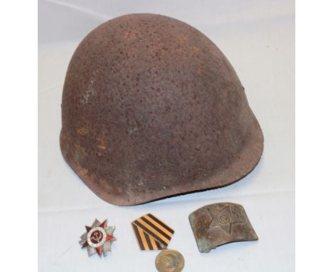 A Second War Russian steel helmet in relic condition, Russian brass rectangular belt buckle, Russian 1941-45 commemorative Wa