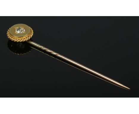 A gold stick pin set with a single diamond and having rope twist border. Tests as high carat.  