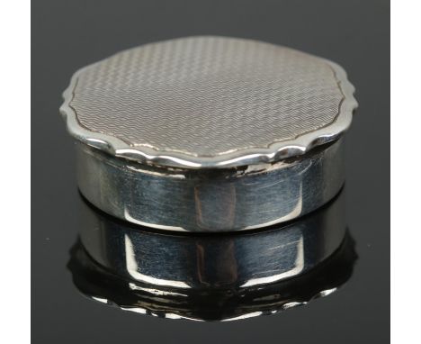 A silver pill box with engine turned engraving to lid. Assayed Birmingham 1933 by William Neale &amp; Sons Ltd. 10.02g.  