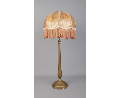 A brass rise and fall table lamp in the style of Benson with fringed shade.  