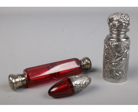 A ruby coloured glass double ended scent bottle with silver top to either side together with similar smaller example and a si