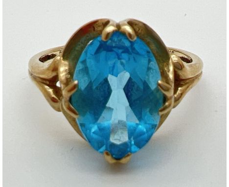 A 9ct gold dress ring set with a large oval cut Swiss blue topaz in a decorative mount. Full hallmarks to inside of band. Rin