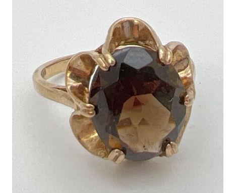 A vintage 9ct gold smoked quartz dress ring set in a fluted style mount. Central oval stone approx. 12mm x 8mm. Ring size N, 