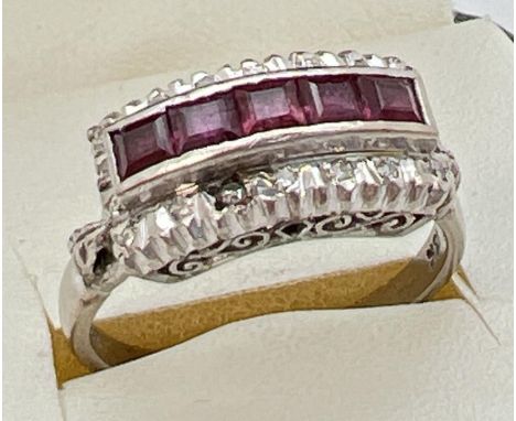 An Art Deco 18ct white gold ruby and diamond dress ring. 5 .16ct square cut rubies in a central high mount surrounded by 18 s