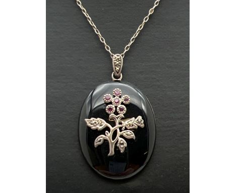 A vintage silver onyx, ruby and marcasite pendant on an 18" fine belcher chain. Oval onyx pendant with silver floral overlay 