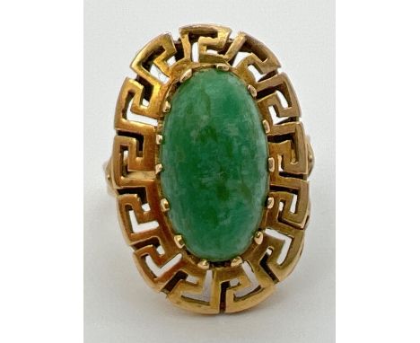 A vintage 14K gold dress ring set with an oval green jade cabochon in a high shoulder decorative oval mount with Greek key de