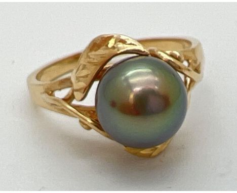 A 14ct gold dress ring set with a large round gunmetal grey pearl. With leaf and vine design mount. Inside of band marked 585