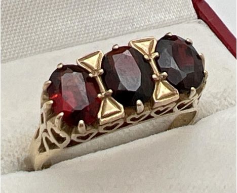 A 9ct gold vintage style garnet set trilogy ring. Decorative high mount with heart design pierced work. Fully hallmarked to b