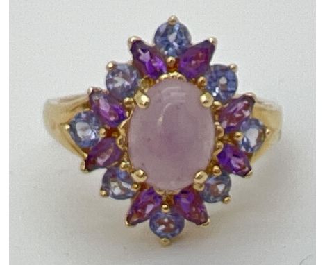 A 14K gold dress ring set with lavender jade, Iolite and amethyst stones. Central oval cabochon of jade surrounded by 8 round