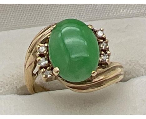 A vintage 14ct gold jade and diamond set dress ring. A twist design mount set with an oval cabochon of green jade with 3 smal