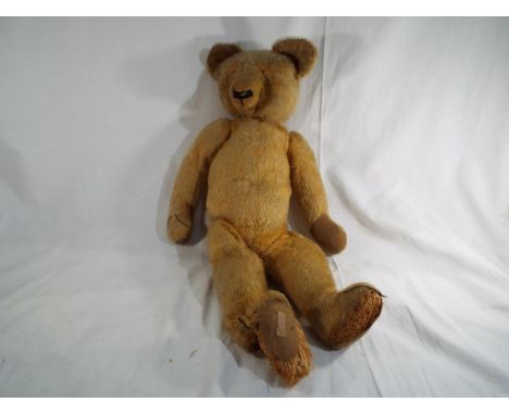 An early 20th century Chad Valley Teddy Bear, straw filled, covered in worn gold plush with swivel joints, stitched snout, gr