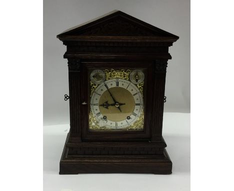 A large oak cased mantle clock with brass dial. Est. £150 - £200.