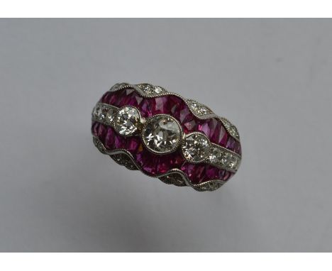 A stylish ruby and diamond cocktail ring with scroll decoration in platinum band. Approx. 6 grams. Est. £1500 - £2000.