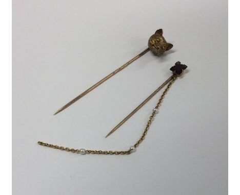 A large gold stick pin set with a fox's head together with one other. Approx. 7.4 grams. Est. £60 - £80.