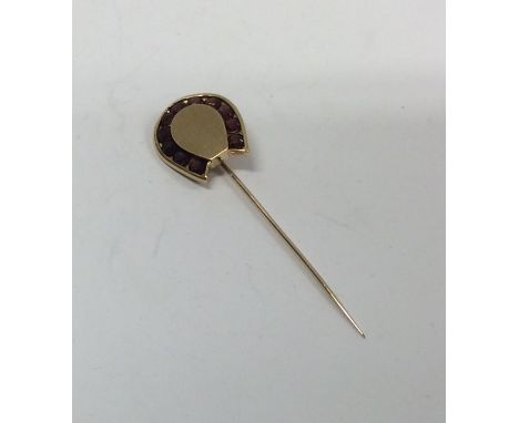 A heavy garnet mounted gold stick pin in the form of a horseshoe. Approx. 5.7 grams. Est. £50 - £80.