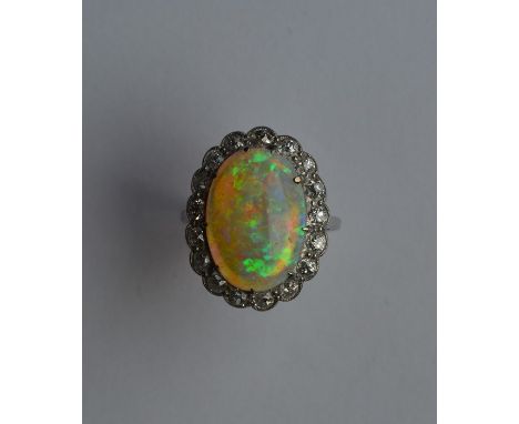 A large cushion shaped opal and diamond oval cluster ring in platinum plain band. Approx. 6.3 grams. Est. £2000 - £3000.