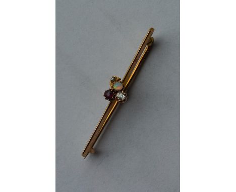 A ruby, opal and diamond brooch in the form of a clover mounted upon a gold bar. Approx. 2.6 grams. Est. £40 - £60.