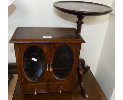 An oak smokers cabinet with double edged oval glass panels to the doors over a pair of drawers together with a mahogany tripo