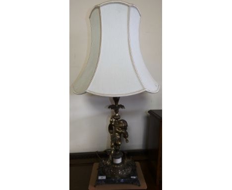 A table lamp with gilded cherub stem over a similar base on marble stand with gilded feet and cream shade