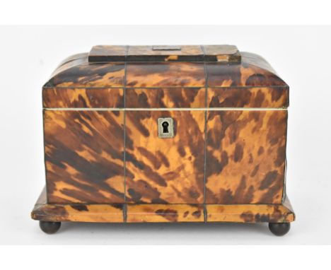 An early 19th century tortoiseshell tea caddy of sarcophagus form, raised on ball feet, 14cm h, 20cm w, 12cm d. Condition: hi