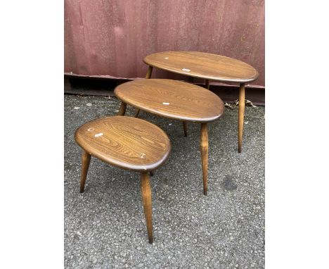 A nest of three mid 20th century Ercol dark stained elm and beechwood 'Pebble' occasional tables, raised on splayed stick sup