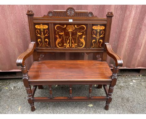 An Art Nouveau mahogany two seater bench having marquetry floral inlaid panels, scrolled shaped arms and turned supports, 106