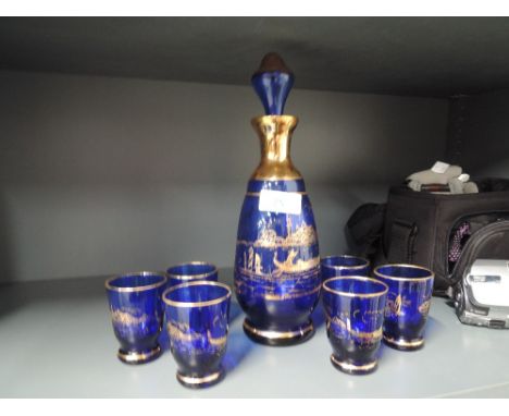 A blue glass decanter with gilt decoration and matching glasses
