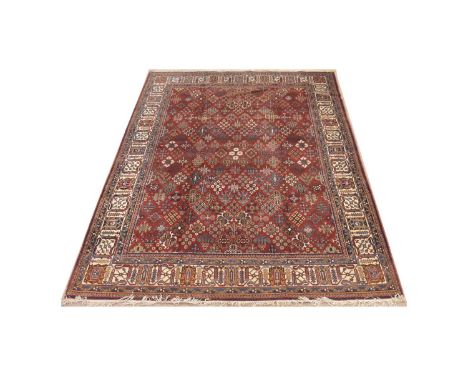 Joshaghan carpet, decorated with floral diamond-shaped panels on a claret ground, 355 x 245cms.