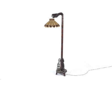 A 20th Century Chinese carved hardwood standard lamp, with a pleated pendant shade suspended from a dragon's head, on leaf an