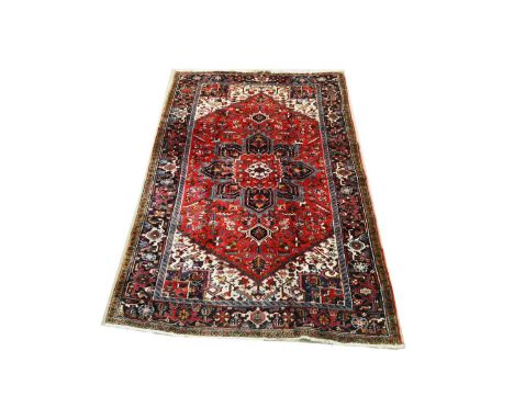 A Heriz carpet, with stylized floral design, on red ground, 299 x 194cms.