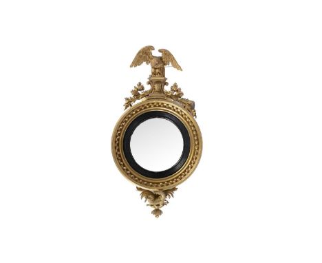A large and decorative Regency gold painted and gesso mirror, the circular combex plate contained within an ebonised slip wit