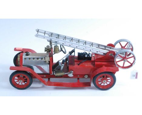 A Mamod live steam fire engine, of usual specification, comprising of red body with red spoked hubs, base metal extending lad