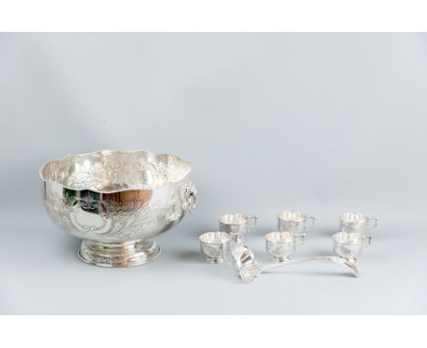 A large bright cut electroplated punch bowl with lion's mask and ring handles to a patterned pedestal base and having six cup