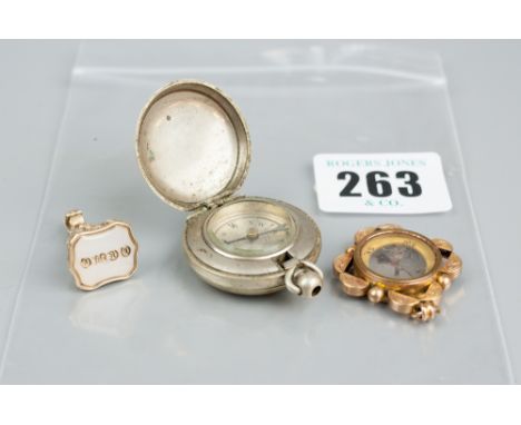 A yellow metal seal fob, a nine carat gold mounted compass pendant and a white metal compass pendant