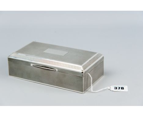 An oblong engine turned silver bound cigarette box with a stepped lid having a Grecian Key style border, Birmingham 1946