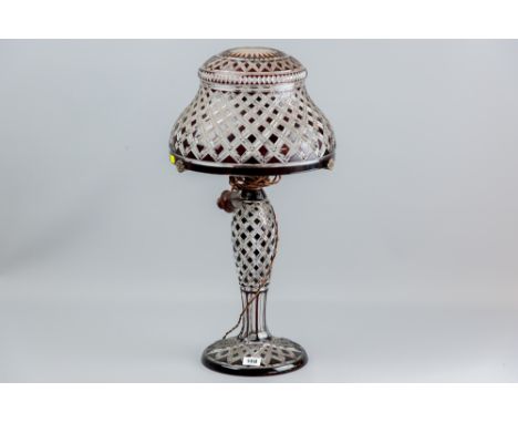 A ruby overlaid and cut glass waisted column lamp with starburst cut domed shade, the shade on a three arm metal holder, 59 c