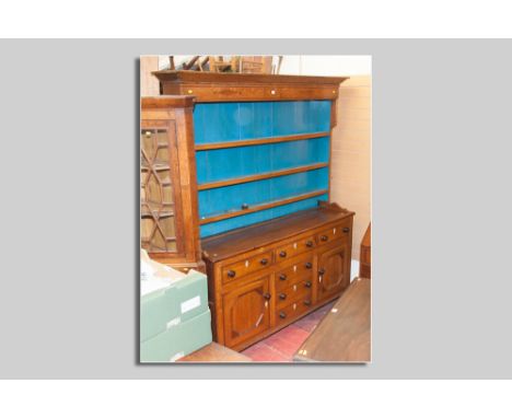 An antique oak straight front Anglesey dresser, three shelf rack over a base of three opening drawers, three false centre dra