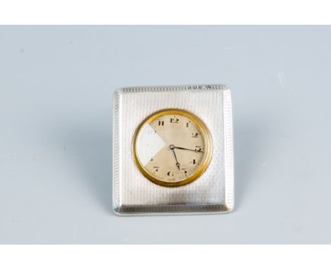 A near square engine turned silver easel clock case, the clock having a circular dial with brass bezel, Birmingham 1923