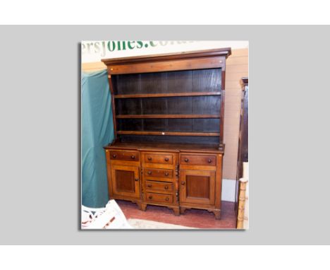 A 19th Century oak and mahogany Welsh dresser having a three shelf rack over a breakfront base having four opening centre dra