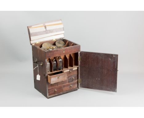 An early 1800's mahogany apothecary cabinet with hinged lid and front and rear opening doors, all revealing various compartme