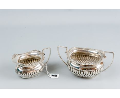 An oblong silver twin handled sugar basin of fluted and reeded form and with a matching milk jug, 13.5 ozs, Chester 1929